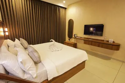 a bedroom with a white bed and a television at Townsquare Residency in Kommeri