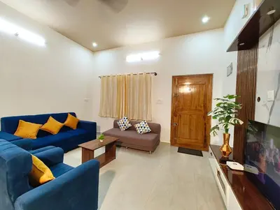 a living room with blue couches and a tv at Namasvi 2Bedroom AC House in Narasimharaja Puram