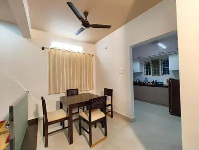 a dining room with a table and chairs and a kitchen at Namasvi 2Bedroom AC House in Narasimharaja Puram