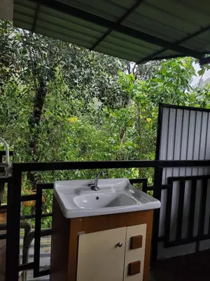 a bathroom sink on a balcony with trees at Maliyeckal Homes in Viripara
