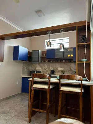 a kitchen with blue cabinets and two chairs at a counter at Villa Vista in Mysore