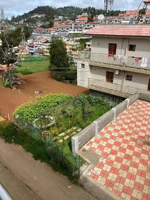 a view of a village with a building and a garden at Essar Cottage in Ooty