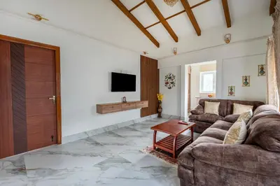 a living room with two couches and a tv at Riverstone Haven in Kotagiri