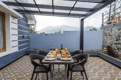 a table and chairs on a patio with a view at Riverstone Haven in Kotagiri