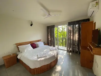 a bedroom with a large bed and a balcony at Tree Valley Resort Wayanad in Meppādi