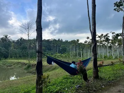 a man sitting in a hammock between two trees at Aquatica by bough'n villa in Kenichira