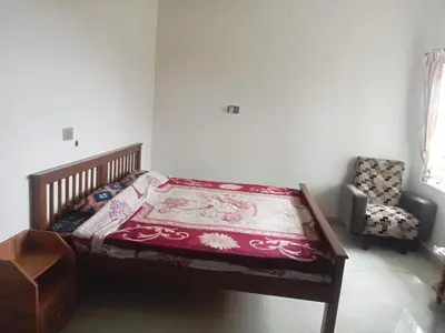 a bedroom with a bed and a chair in a room at Cherry Blossom in Kotagiri