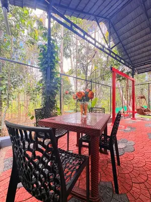 a table with chairs and a vase of flowers on a patio at sahara dua jungle farmstay in Wayanad