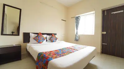 a bedroom with a bed with a mirror and a window at Aangal residency in Coimbatore