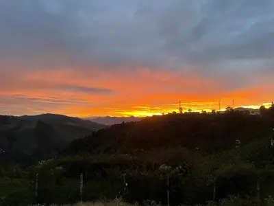 a sunset on top of a mountain with the sun setting at Balacalava Guest House in Coonoor