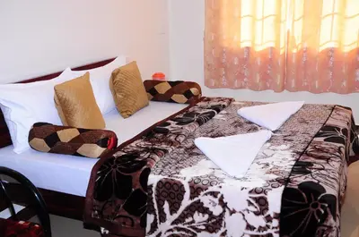 a bed with a comforter and pillows on it at A L Residency in Ooty