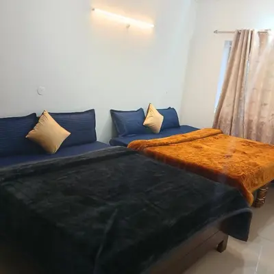 a room with two beds and a couch with a table at A L Residency in Ooty