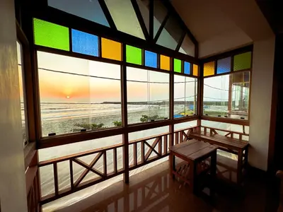a room with a window with a bench and a view of the beach at SeaCret by Dormer Stay in Kozhikode