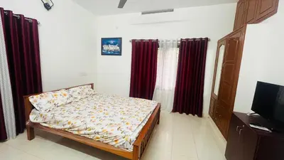 a small bedroom with a bed and red curtains at Johnnys Destination in Angamali