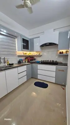 a kitchen with white cabinets and a stove top oven at Kulipini Family Apartment in Irinjālakuda