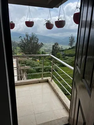 a view from a door of a balcony with hanging baskets at Hideaway Home43 in Ooty