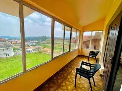 an empty room with two chairs and large windows at Teyt Castle - Ooty - Nilgiris in Ooty