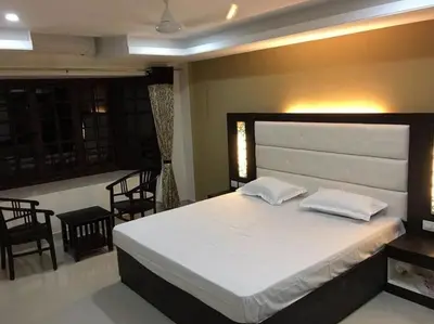 a bedroom with a large white bed and chairs at Hotel TriColors Ramnagar Gandhipuram in Coimbatore