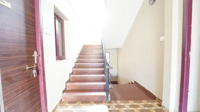 a staircase in a building with a wooden door at Airport Home Stay in Coimbatore