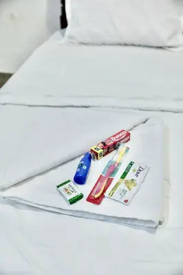 a bed with a white blanket with toothpaste and toys on it at Idanazhi the corridor in Kozhikode