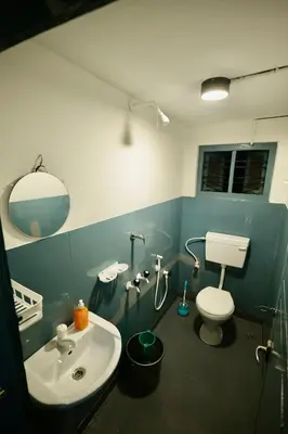 a bathroom with a white toilet and a sink at Idanazhi the corridor in Kozhikode