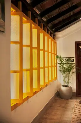 a wall with yellow windows in a room with a potted plant at Idanazhi the corridor in Kozhikode