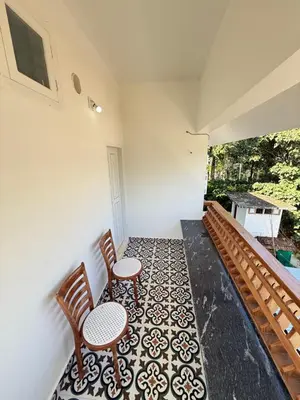 a balcony with two chairs and a table at Paradise Premium Villa Munnar in Munnar