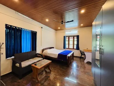 a bedroom with a bed and a couch and a table at whisperingstrem's RIVER view homestay in Padinjarathara