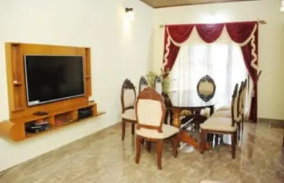a living room with a table and chairs and a television at Cozy Coffee Estate Homestay Coorg Madikeri in Madikeri