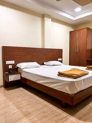 a bedroom with a large bed with a wooden headboard at Shri Amman Residency in Dhārāpuram