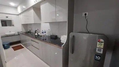 a kitchen with a stainless steel refrigerator and white cabinets at Lavender Airport suite in Nedumbassery