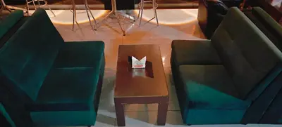 a table with two green chairs and a paper on it at RR Grand Inn in Coimbatore