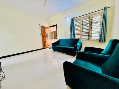 a living room with two blue chairs and a couch at Rohi stays 2 bed room flats in Mysore