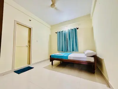 a bedroom with a bed with a blue curtain at Rohi stays 2 bed room flats in Mysore