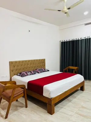 a bedroom with a large bed and a chair at Apple Tower Stays in Meppādi