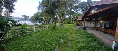 a yard next to a building with a grass field at Grace Backwater Villa Coorg in Suntikoppa