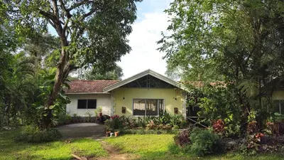 a yellow house with trees in front of it at Grace Backwater Villa Coorg in Suntikoppa
