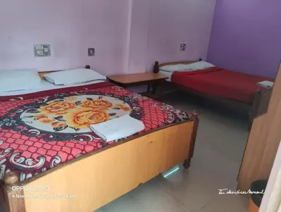 two beds in a room with two tables and a bed sidx sidx sidx at Hotel Srusti Residency in Mysore