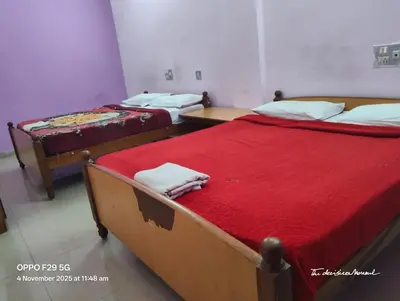 two beds with red sheets in a room at Hotel Srusti Residency in Mysore