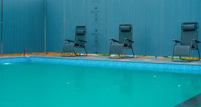 a row of chairs in a swimming pool at Rivera resort and wellness center in Kodanad
