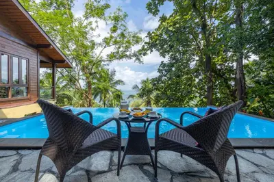 a patio with a table and chairs next to a pool at amã Stays & Trails - Iris Villa, Kozhikode in Puthuppādi
