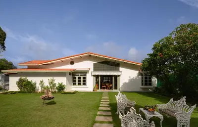 a white house with two white chairs in the yard at amã Stays & Trails - Mount Pleasant, Coonoor in Coonoor