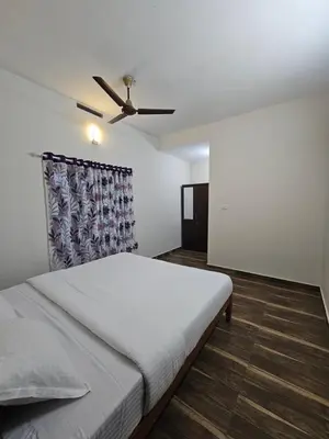 a bedroom with a bed and a ceiling fan at Mount Wave Holiday Pool Villa in Wayanad