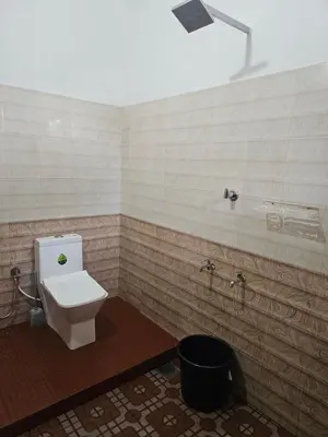a bathroom with a toilet and a trash can at Mount Wave Holiday Pool Villa in Wayanad