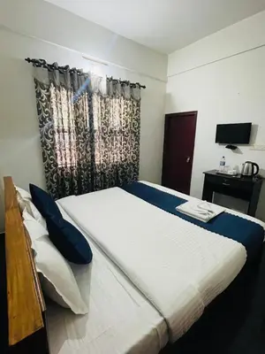 a bedroom with a large white bed with blue pillows at Vythiri saara inn in Vythiri