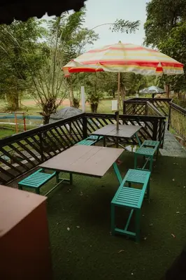 two picnic tables and chairs with an umbrella at Greenex farm Resort in Vythiri