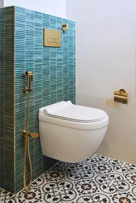 a bathroom with a toilet and a blue tiled wall at Okka by Raho - A colonial style villa in Coorg in Siddapur