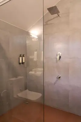 a bathroom with a shower with a toilet and a sink at Nila by Raho - Secluded Villa with Estate View in Siddapur