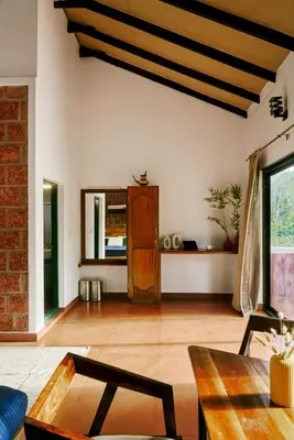 a living room with a table and a couch at Nila by Raho - Secluded Villa with Estate View in Siddapur
