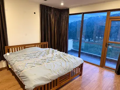 a bedroom with a bed and a large window at LaFiesta in Kodaikānāl
